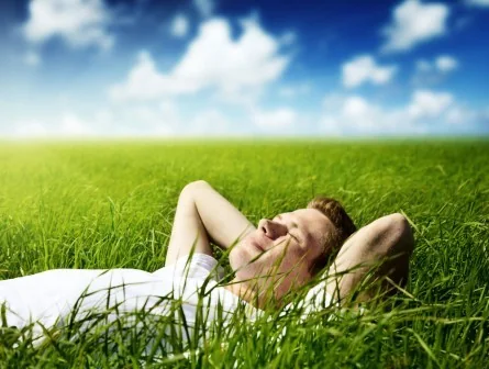 Original booklet photograph of a woman resting on grass beneath a blue sky.